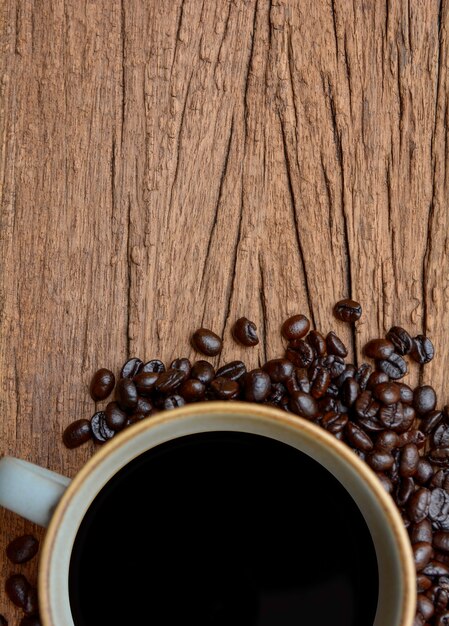 Vue de dessus du grain de café avec une tasse de café sur fond de bois