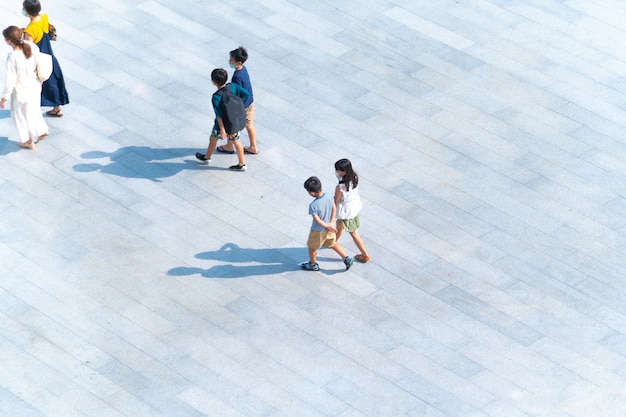 Vue de dessus du groupe de mères et d'enfants marchant sur une passerelle piétonne en plein air pour voyager