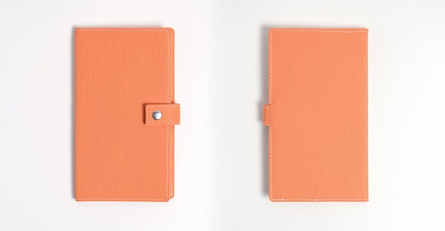 Vue de dessus du journal en cuir orange vierge sur un bureau blanc