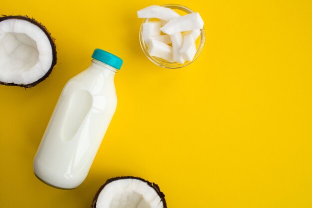 Vue de dessus du lait de coco dans la bouteille en verre sur le jaune