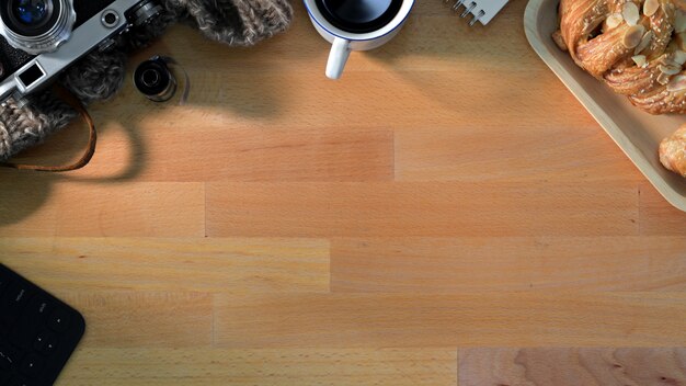 Vue de dessus du lieu de travail avec des fournitures de bureau, petit déjeuner avec espace copie sur table en bois