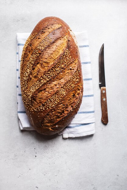 Vue de dessus du pain artisanal aux graines de sésame sur une serviette Fond gris