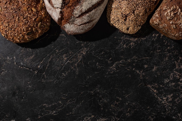 Vue de dessus du pain de grains entiers frais cuit au four sur une surface noire en pierre
