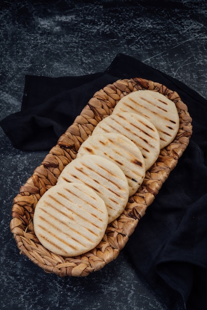 Vue de dessus du panier tressé rempli d'un groupe d'arepas d'Amérique latine sur fond sombre