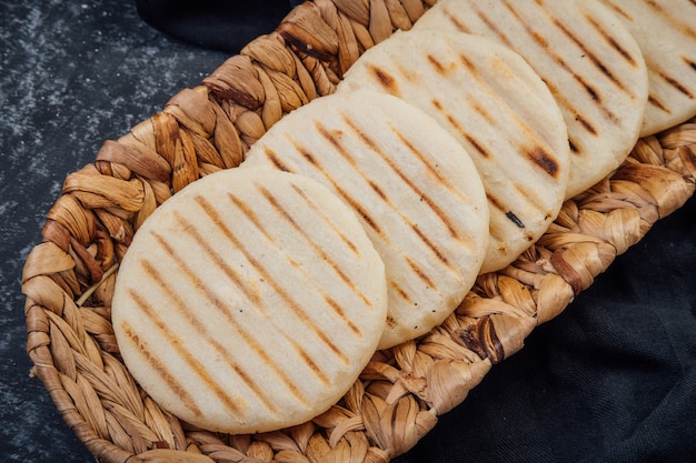 Vue de dessus du panier tressé rempli d'un groupe d'arepas d'Amérique latine sur fond sombre