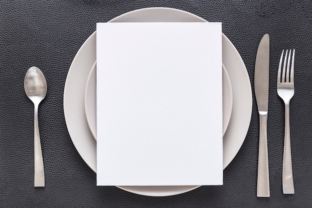 Photo vue de dessus du papier de menu vierge sur plaque avec fourchette et couteau