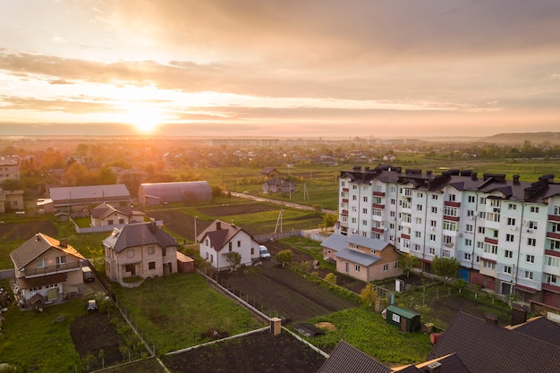 Vue de dessus du paysage urbain en développement. Immeubles d'habitation et de maisons de banlieue sur ciel rose à fond de lever de soleil.