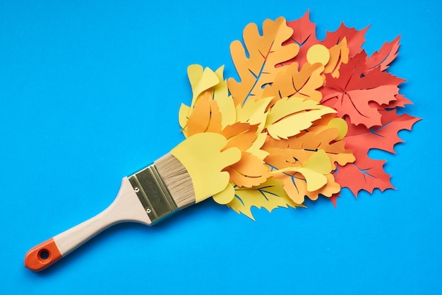 Vue de dessus du pinceau chargé de feuilles d'automne sur papier bleu