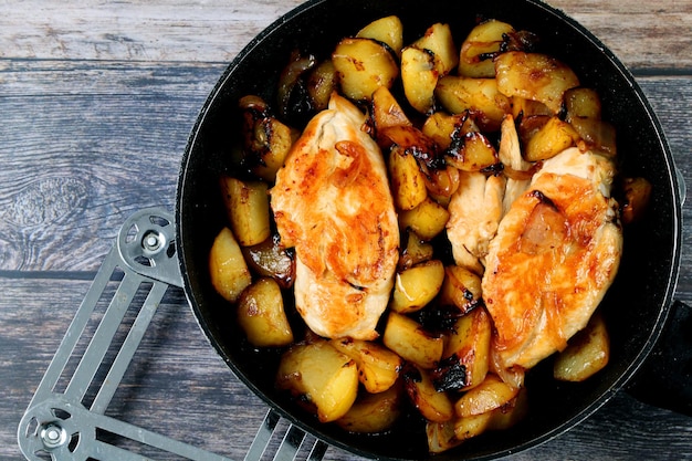 Vue de dessus du poisson frit et des pommes de terre dans une casserole sur une surface en bois