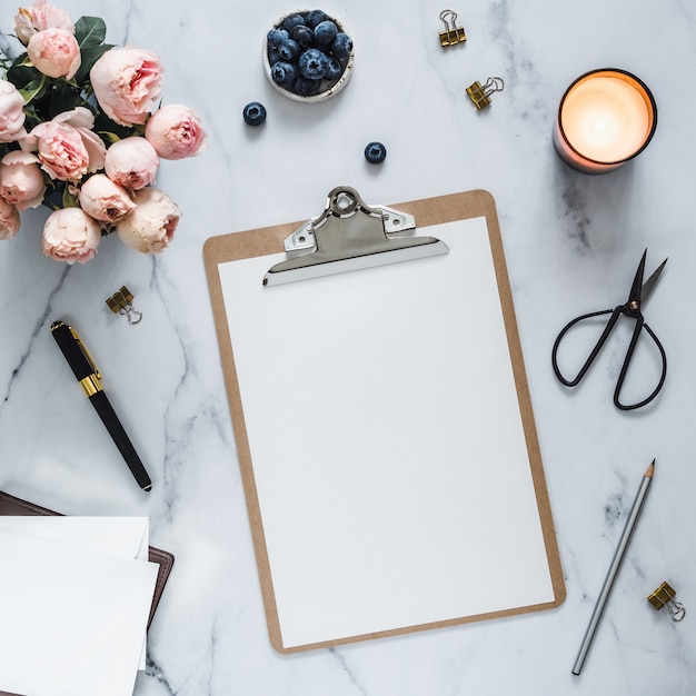 Vue De Dessus Du Presse-papiers Avec Une Page Vide Blanche. Presse-papiers, Fleurs, Bougie Parfumée Sur Marbre Blanc.