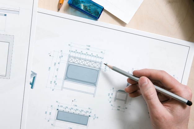 Vue de dessus du processus de travail du concepteur. Main qui écrit un modèle de conception sur schéma de dessin.