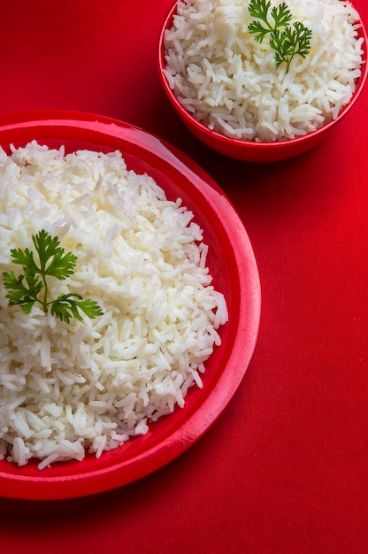 Vue de dessus du riz basmati blanc cuit dans un bol et une assiette rouge