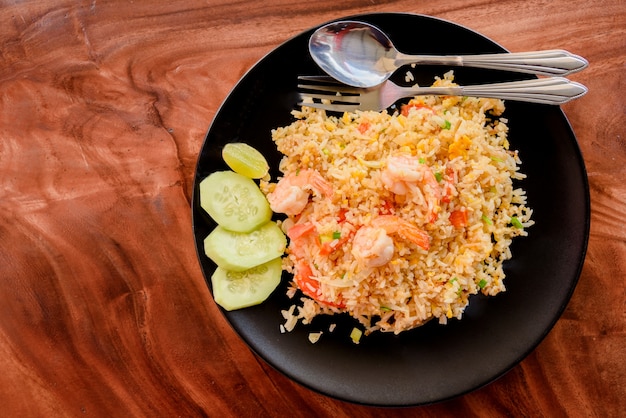 Vue de dessus du riz frit avec des crevettes sur le plat sur la table en bois