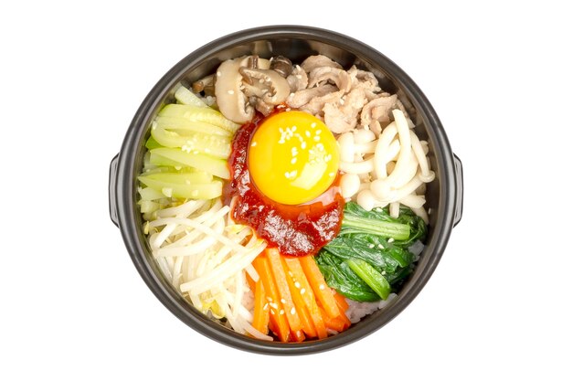 Vue de dessus du riz mixte coréen fait maison appelé Bibimbap servi dans un pot en pierre chaude isolé sur blanc