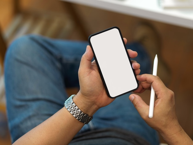 Vue de dessus du smartphone holding male comprennent un écran de chemin de détourage et un stylet dans sa main