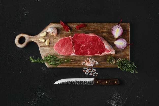 Vue de dessus du steak de bœuf de surlonge cru sur une planche à découper en bois