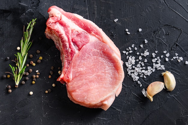 Vue de dessus du steak de côtelette de porc biologique cru avec des ingrédients