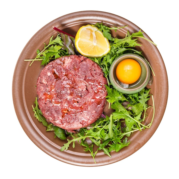 Vue de dessus du steak tartare sur plaque brune isolé