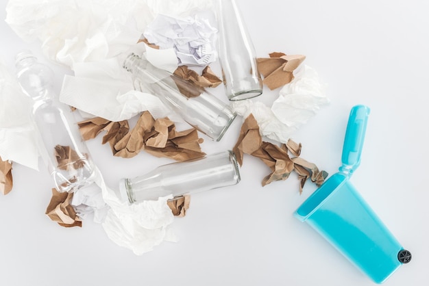 Vue de dessus du verre de poubelle jouet bleu et du papier de bouteilles en plastique sur fond gris