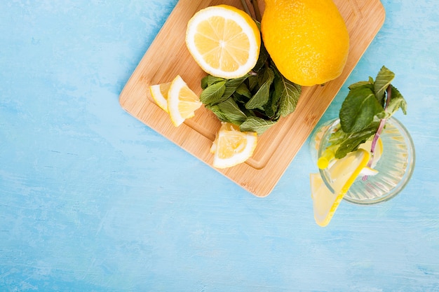 Vue de dessus de l'eau de désintoxication biologique fraîche avec des citrons sur fond de bois vintage bleu