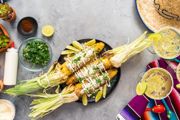 Vue de dessus. Elote de maïs de rue mexicaine grillée garnie d'épices sur une assiette de service.