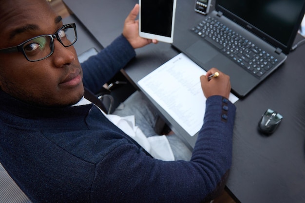 Vue de dessus d'un employé africain travaillant avec une tablette assis à un bureau