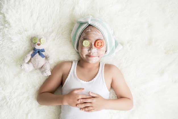 Vue de dessus Enfant asiatique petite fille porte une serviette turbine et un masque facial au concombre