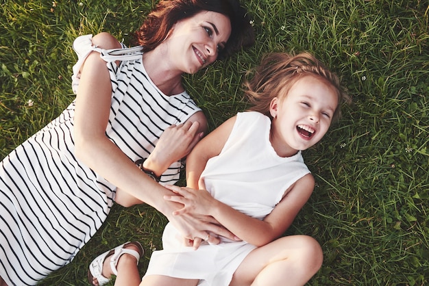 Vue de dessus des enfants et de la mère allongés sur l'herbe remplie de soleil et se regardant