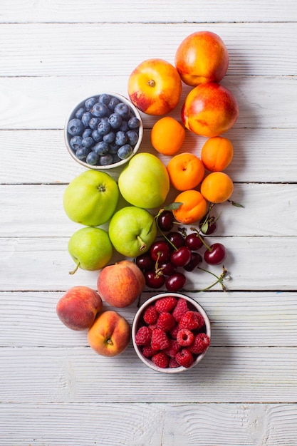 Vue de dessus sur un ensemble de différents fruits traditionnels étalés sur une surface en bois blanche