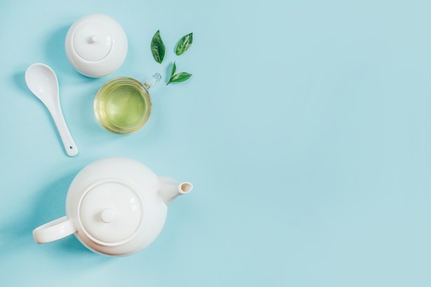 Vue de dessus d'un ensemble d'ustensiles de thé théière sucrier tasse avec du thé sur une surface bleue