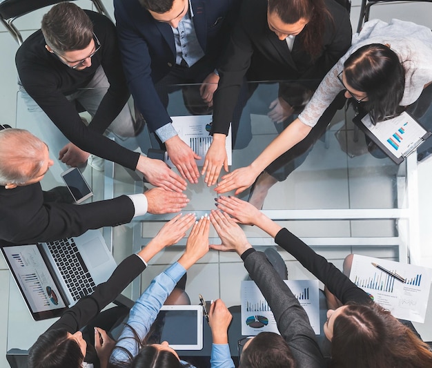 Vue de dessus. équipe commerciale joignant leurs mains en cercle sur le bureau.