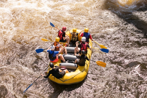 Photo vue de dessus d'une équipe de rameurs avec des avirons surmonte les rapides sur une rivière orageuse sur un bateau de rafting