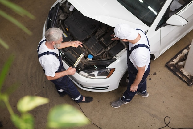 Photo vue de dessus d'une équipe de travailleurs de l'entretien automobile réparant une automobile