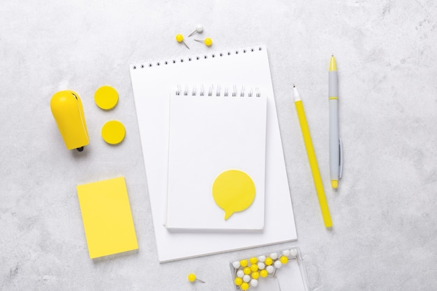Vue de dessus de l'espace de travail avec bloc-notes et accessoires de papeterie sur fond de pierre grise. Illuminating Yellow et Ultimate Grey, couleurs de l'année 2021 - Image