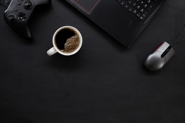 Vue de dessus de l'espace de travail de bureau gamer avec tasse à café et ordinateur portable sur tableau noir