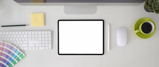 Vue de dessus de l'espace de travail de concepteur graphique avec tablette à écran vide, appareil informatique et fournitures de concepteur