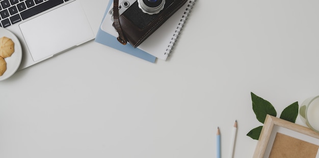 Vue de dessus d'un espace de travail confortable avec des fournitures de bureau sur fond de tableau blanc