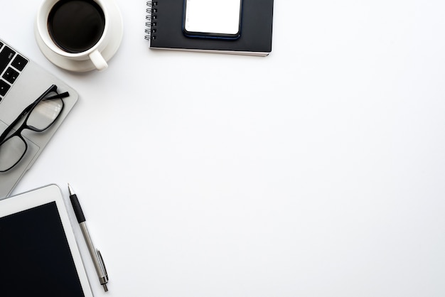 Vue de dessus d'un espace de travail créatif avec un smartphone placé sur une tablette de café. Bureau blanc