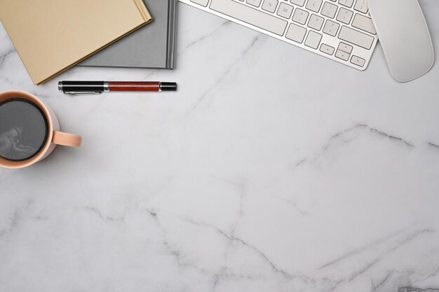 Vue de dessus espace de travail femme avec tasse de cahiers à café et clavier sur table en marbre