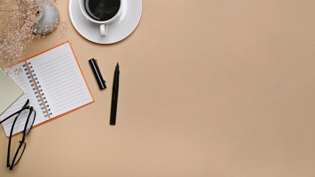 Vue de dessus de l'espace de travail simple tasse de café et cahier sur fond beige