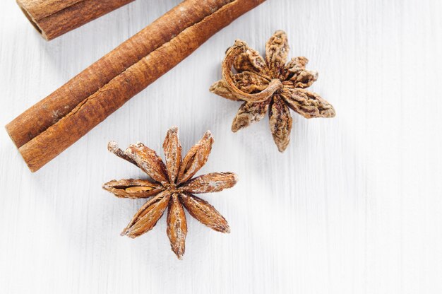 Photo vue de dessus: étoiles d'anis et bâtons de cannelle sur une surface en bois blanche