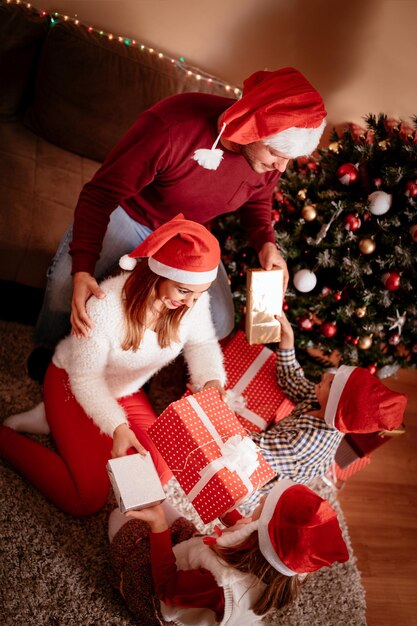 Vue de dessus d'une famille heureuse qui se donne des cadeaux pour Noël à la maison.