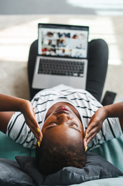 Vue de dessus d'une femme africaine ayant mal à la tête après beaucoup de travail informatique en freelance
