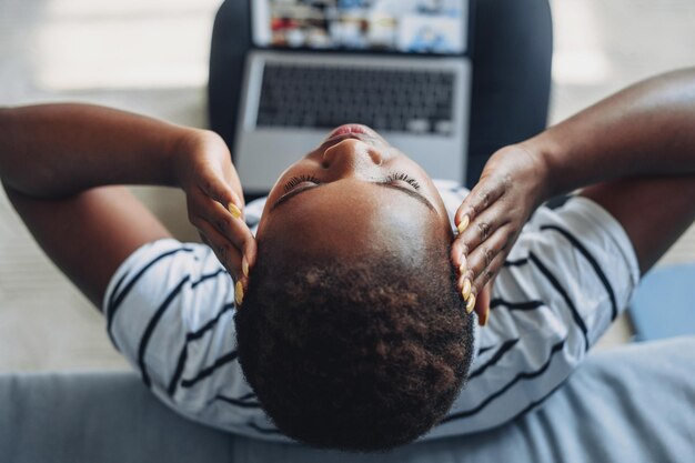 Vue de dessus femme afro-américaine assise sur le sol attrapant la tête souffrant de maux de tête tout en utilisant un ordinateur portable Souffrant de migraine Mains sur la tête