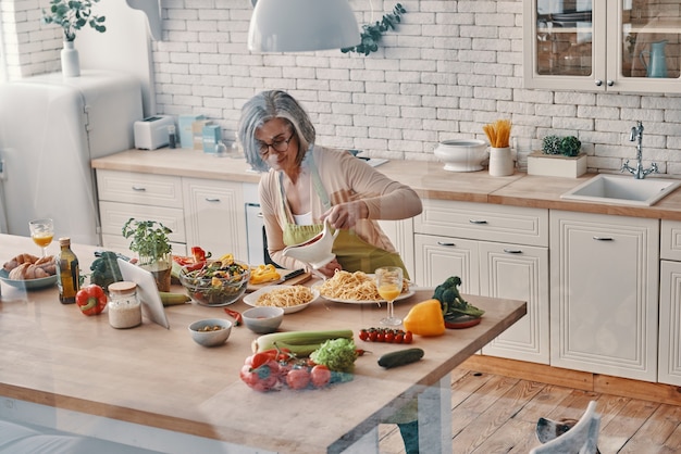 Vue de dessus d'une femme âgée en tablier préparant un dîner sain tout en passant du temps à la maison