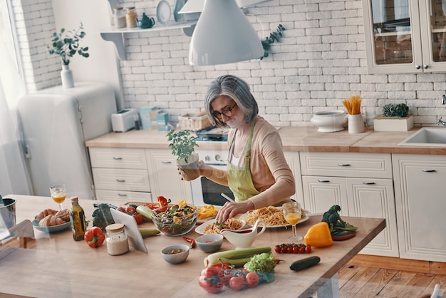 Vue de dessus d'une femme âgée en tablier préparant un dîner sain tout en passant du temps à la maison