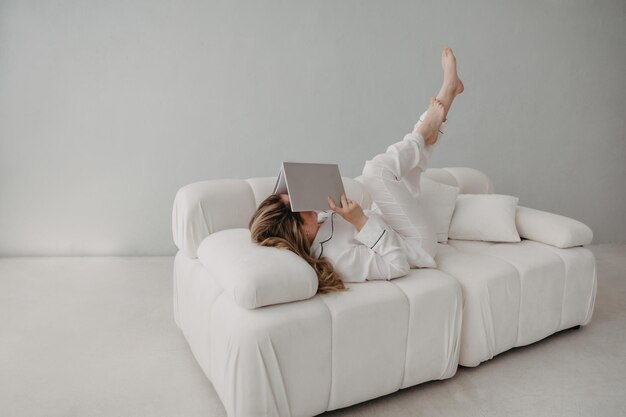 Vue de dessus d'une femme allongée sur un canapé avec un livre