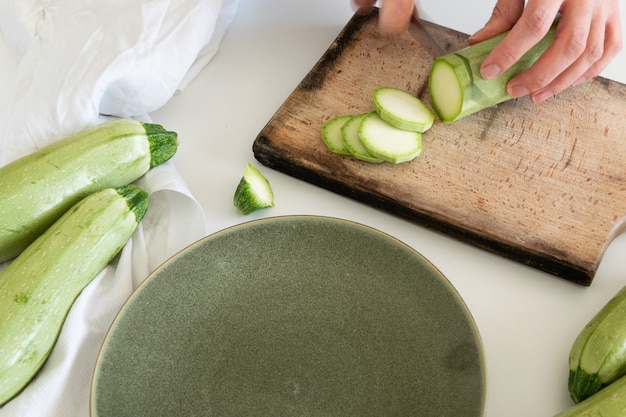 Vue de dessus d'une femme coupant des courgettes fraîches et mûres