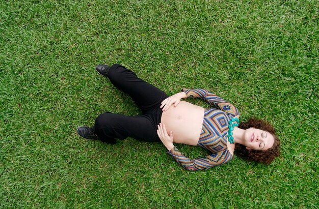 Vue de dessus de la femme enceinte allongée dans l'herbe avec espace de copie