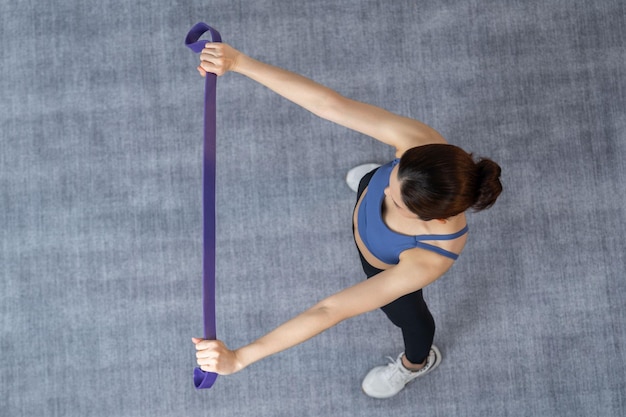 Vue de dessus femme énergique vigoureuse faisant de l'exercice sur fond de surface de tapis étirement bande de sport de résistance Jeune femme asiatique athlétique force et endurance comme routine d'entraînement à domicile